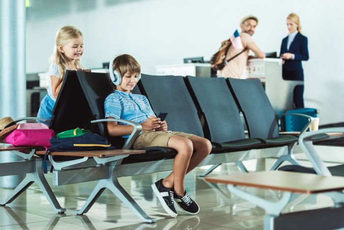 niño usando móvil en una sala de espera de aeropuerto
