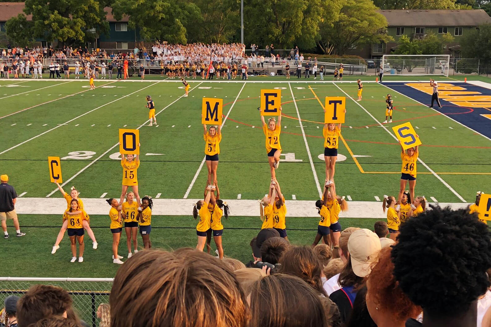 Equipo de animadoras, sujetan letreros con la palabra "Comets", durante un partido de fútbol americano