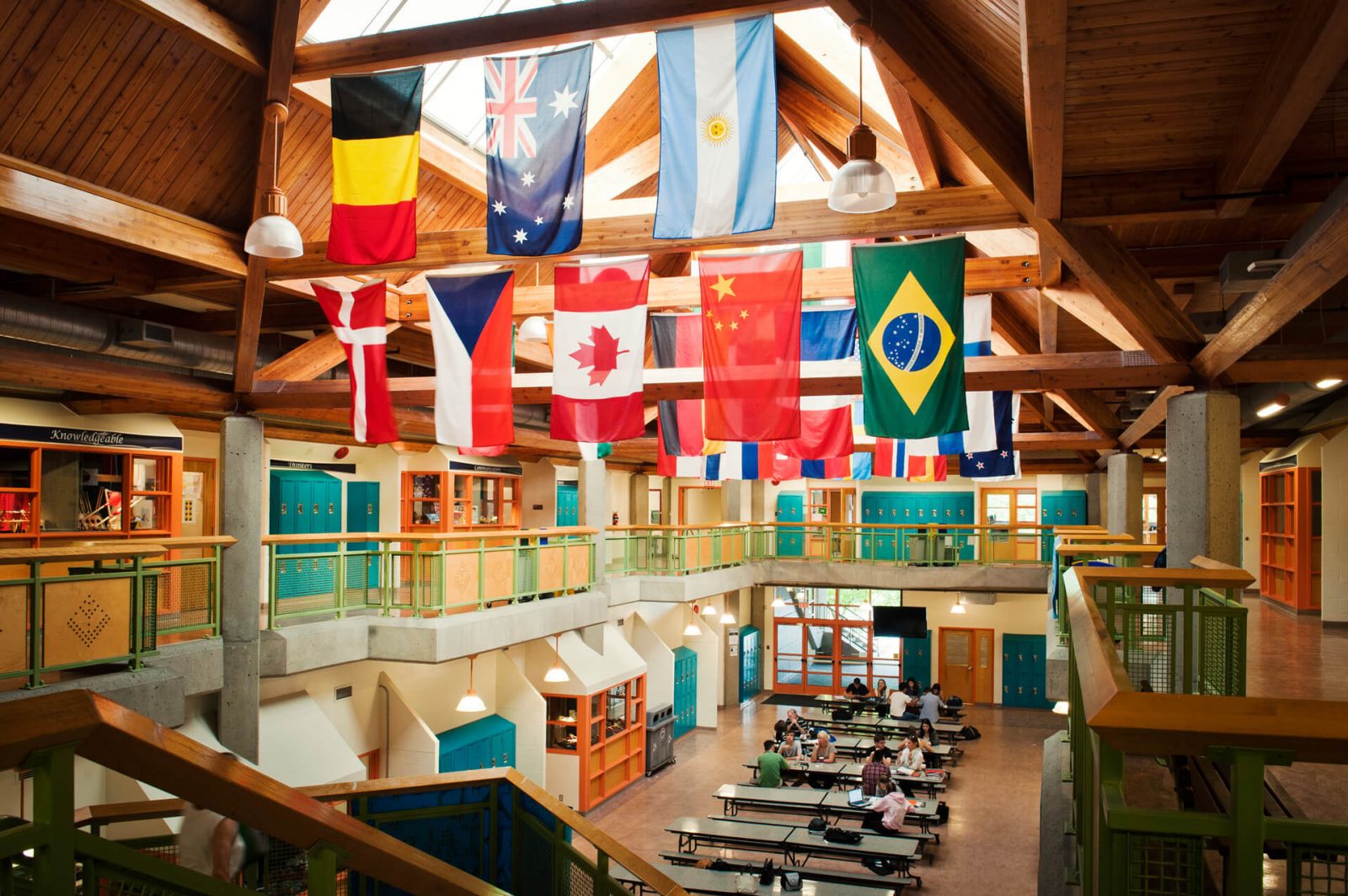 Hall principal de instituto, con taquillas y banderas de distintos países colgando del techo