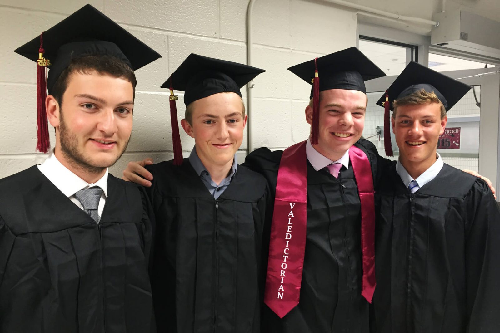 Cuatro estudiantes amigos en túnica, recién graduados