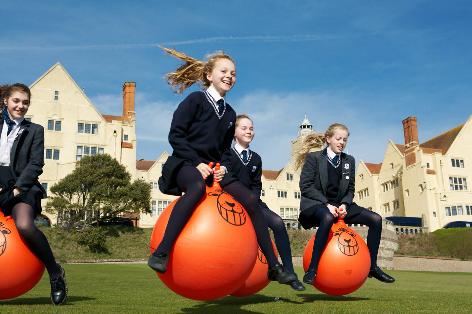 Cuatro compañeras de internado, saltando sobre pelotas naranjas fuera del colegio - Rodean School