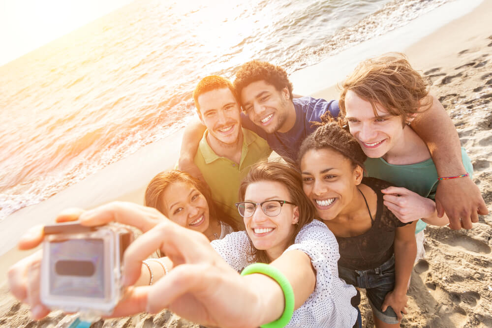 grupo de amigos haciéndose selfie en la playa