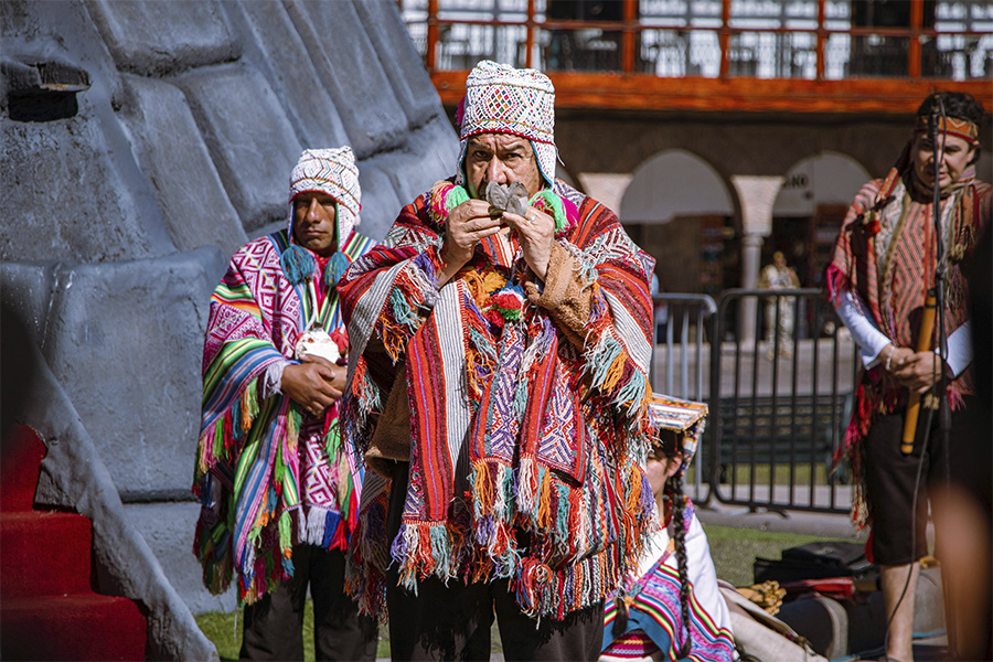 Hombres con vestimenta tradicional andina realizando una ceremonia ritual al aire libre.