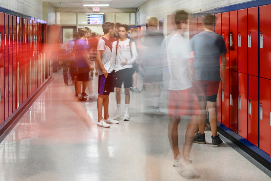 Pasillo de un instituto internacional con filas de taquillas rojas y estudiantes en movimiento durante el cambio de clase.