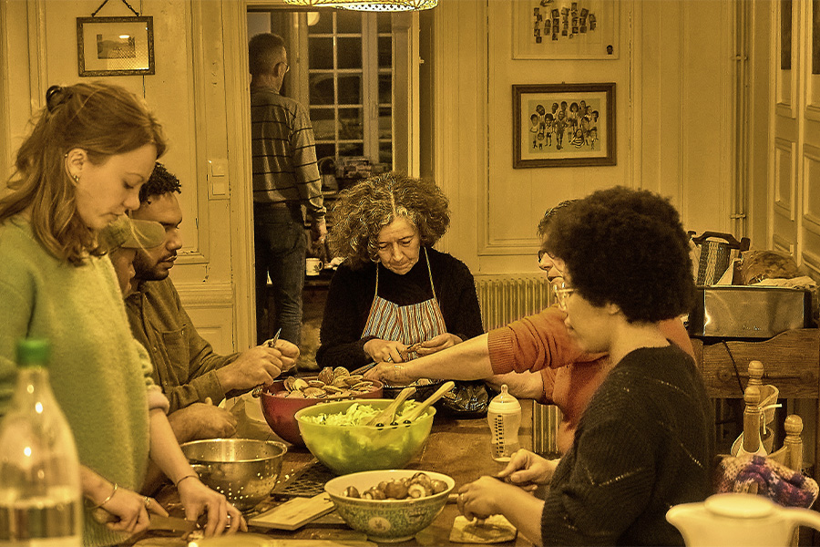 Un grupo de personas compartiendo la tarea de cocinar en una mesa rústica, ilustrando el apoyo mutuo y los hábitos colectivos.