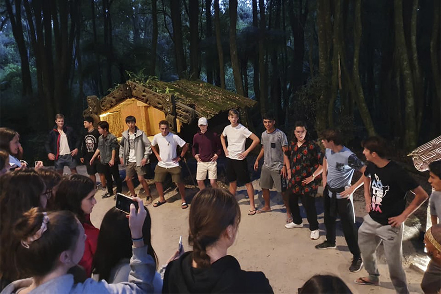Grupo de jóvenes estudiantes internacionales realizando un Haka tradicional Maorí durante un campamento en Nueva Zelanda.