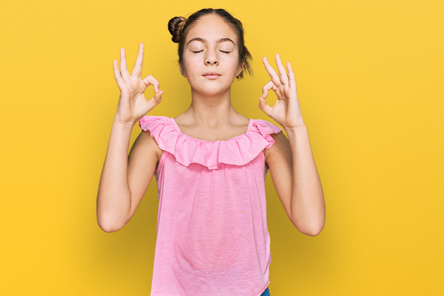 Joven con los ojos cerrados realizando un gesto de calma y meditación, representando la regulación emocional.