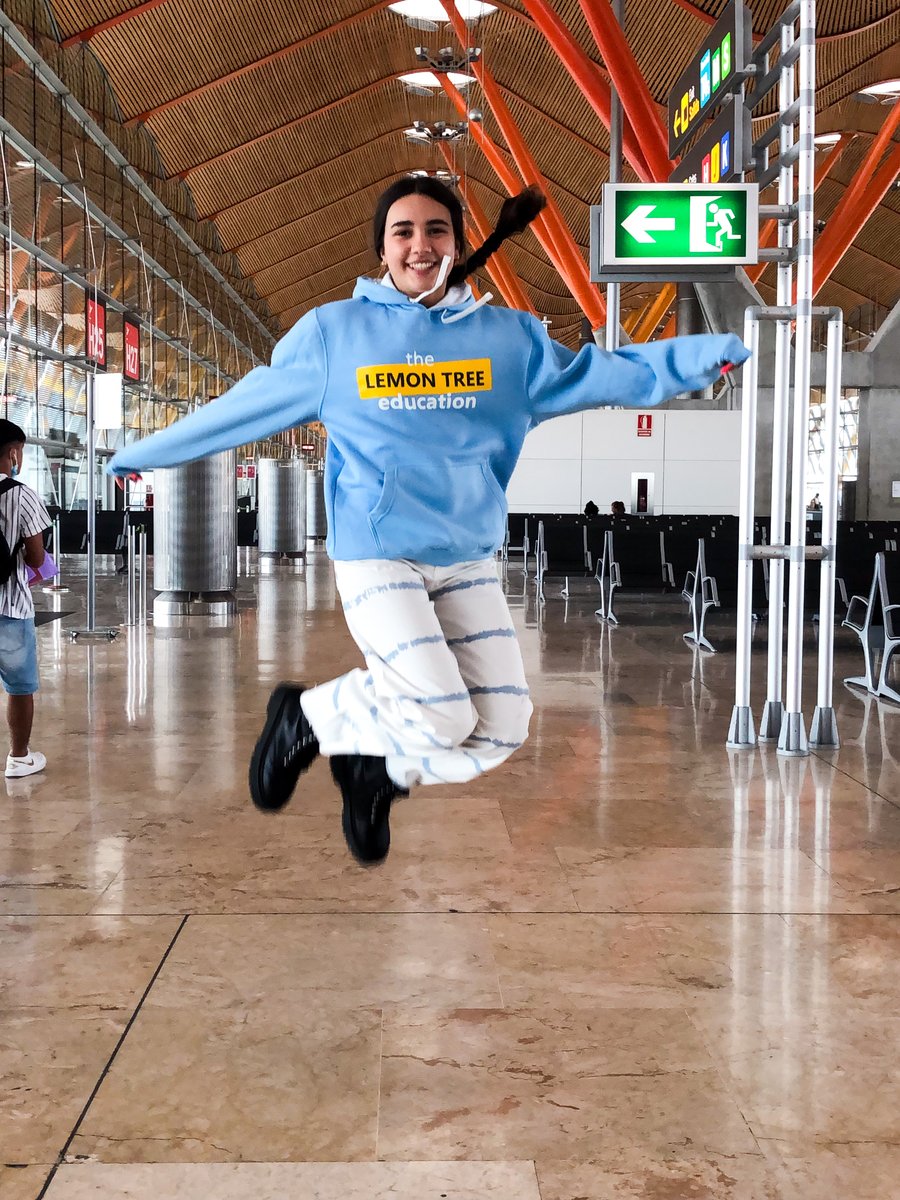 Estudiante saltando de alegría en la terminal antes de volar a su año escolar